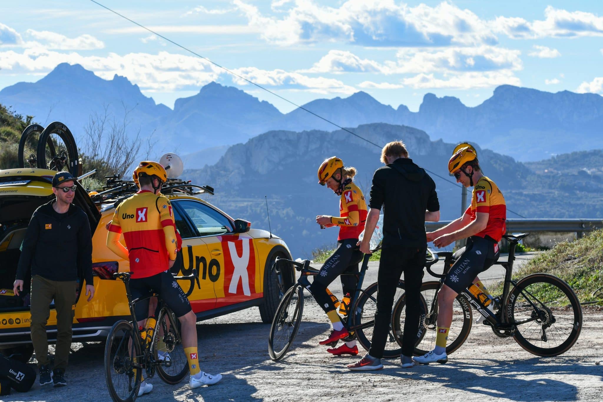Uno-X-ryttere gjør seg klare ved lagbilen med fjellene på Costa Blanca i bakgrunnen